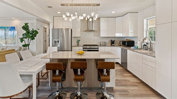 A modern kitchen with a central island, bar stools, stainless steel appliances, and a herringbone-patterned backsplash. - Golden Isles Getaway -**ASK ABOUT SNOWBIRD SPECIALS** (Brunswick)
