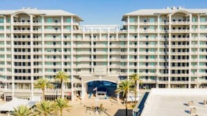 A large, multi-story hotel with a symmetrical facade, numerous balconies, and a central entrance. - Wharf 703|Waterfront View|2 bedroom|Pool|sleeps 8! (Orange Beach)