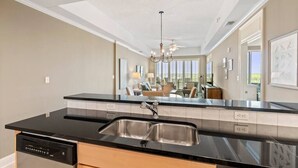 A modern kitchen with a black countertop, stainless steel sink, and a dishwasher. - Wharf 703|Waterfront View|2 bedroom|Pool|sleeps 8! (Orange Beach)