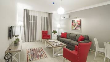 A modern living room with a grey sofa, red armchairs, a wooden coffee table, and a patterned rug.
