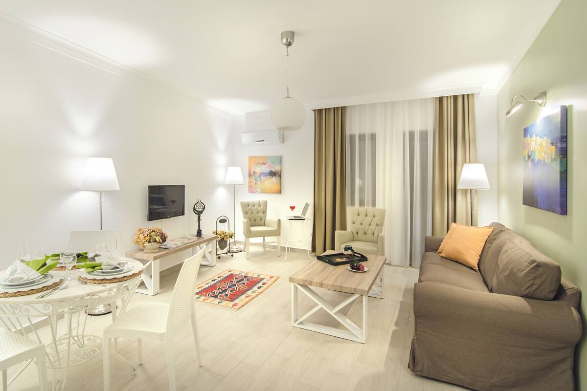 A modern living room with a sofa, a dining table set for two, a coffee table, and a TV.