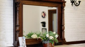 A wooden vanity with a mirror, a potted plant, and a framed picture. - Rodina Suites (Kusadasi)