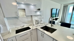 A modern kitchen with a marble countertop, a sink, and a built-in oven. There is a window with a view of the outside. - Caribbean Beach front King bed with large balcony (Luquillo)