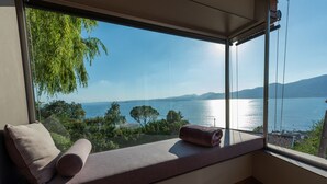 A room with a large window offering a view of a lake and distant mountains. - Luxury Villa Vela (Torri del Benaco)
