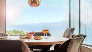 A dining table with a view of the mountains, a bowl of appetizers, and two glasses of wine. - Luxury Villa Vela (Torri del Benaco)