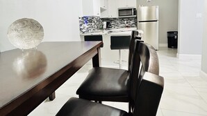 Una cocina moderna con armarios blancos, un refrigerador de acero inoxidable y un microondas.