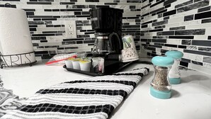 Una cocina con cafetera, un tapete a rayas y salpicadero de azulejos.