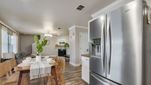 Une cuisine moderne avec un réfrigérateur en acier inoxydable, une table à manger en bois et des chaises.