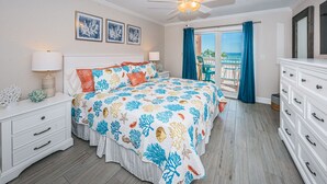 A bedroom with a bed, nightstands, a dresser, a ceiling fan, and a view of the outdoors. - 🌴HEATED POOL AND JACUZZI FOR YEAR ROUND RELAXATION ON OCEAN FRONT BEACH⛱️ 
 (Indian Shores)