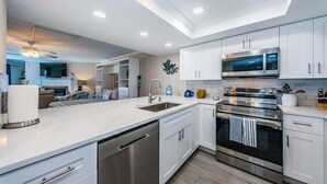A modern kitchen with white cabinets, stainless steel appliances, and a central island with a sink. - 🌴HEATED POOL AND JACUZZI FOR YEAR ROUND RELAXATION ON OCEAN FRONT BEACH⛱️ 
 (Indian Shores)