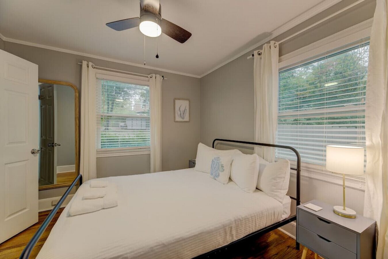 Un dormitorio con cama, mesita de noche, lámpara y ventilador de techo.