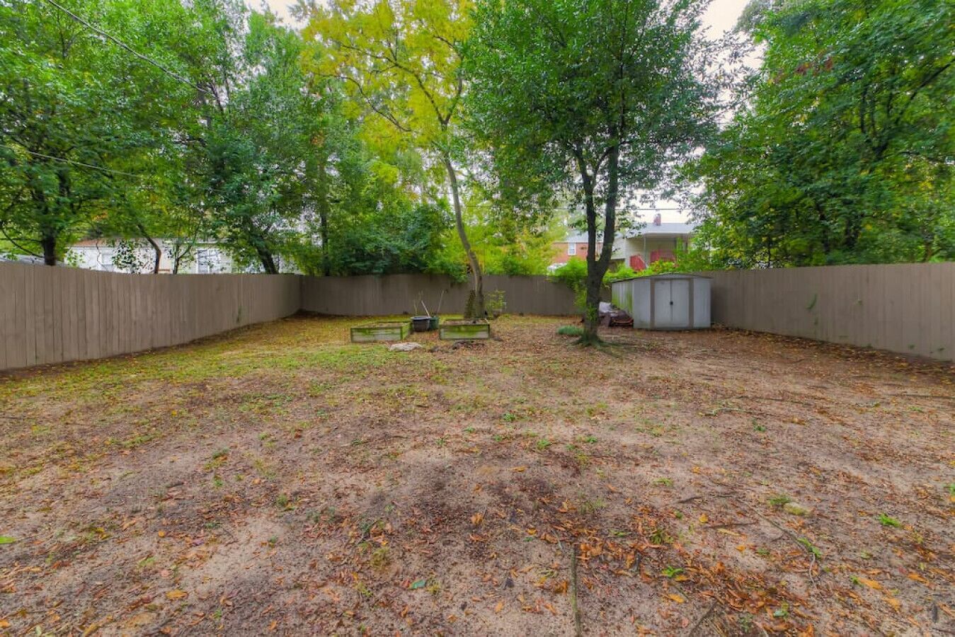 A backyard with a wooden fence, a shed, and trees.