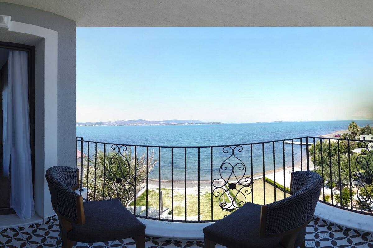 A balcony with two chairs and a view of the sea.