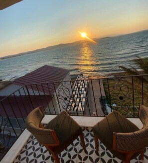 A terrace with a view of the sunset over the sea, featuring a table and two chairs. - Houdini Otel (Urla)