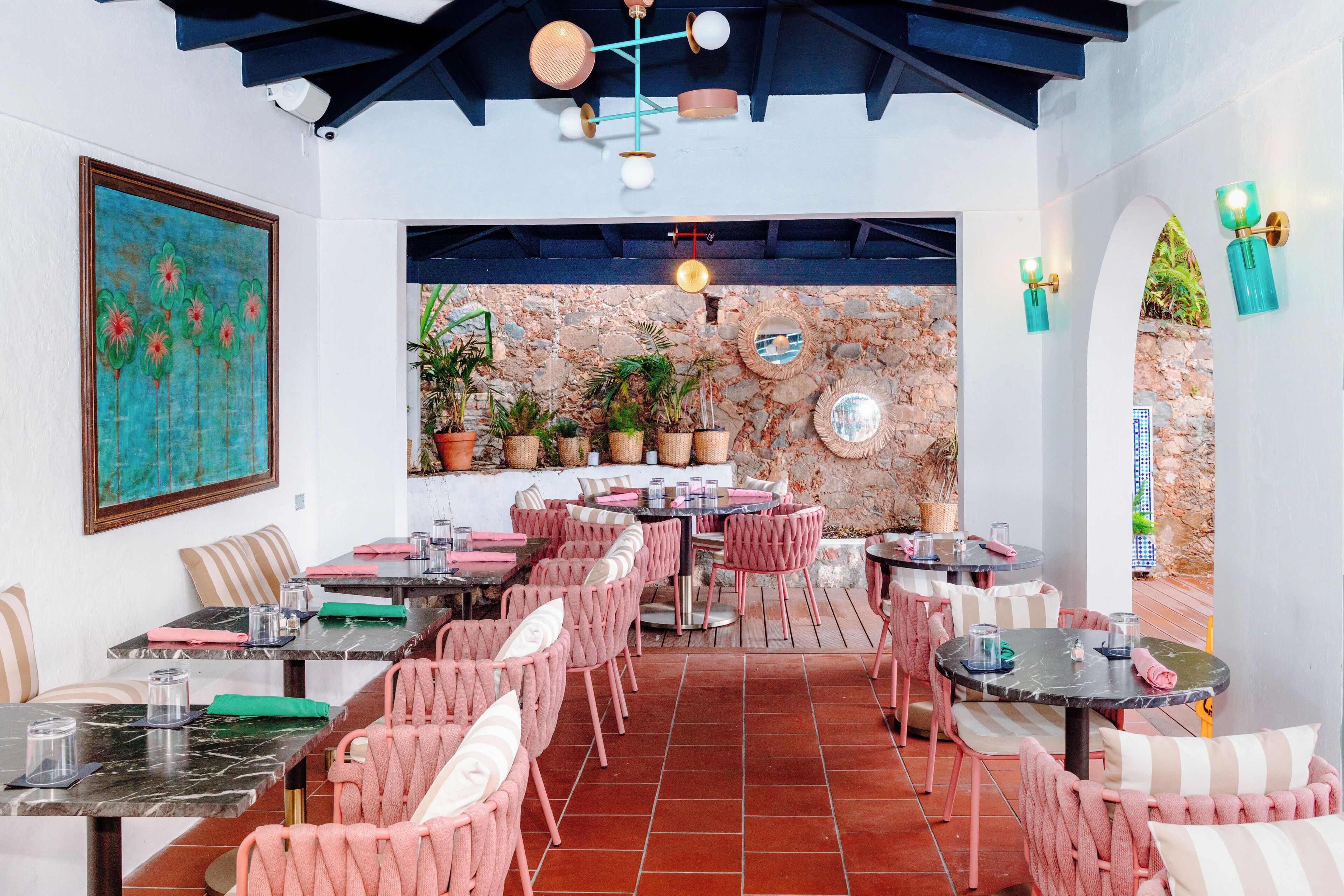 A restaurant with outdoor seating, stone walls, and potted plants.