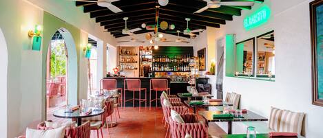 A restaurant interior with tables, chairs, ceiling fans, and a bar area.