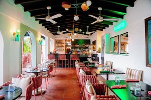 A restaurant interior with tables, chairs, ceiling fans, and a bar area.