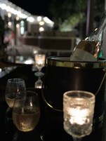 Un bar con una botella de champán, dos copas de vino y una vela sobre una mesa.