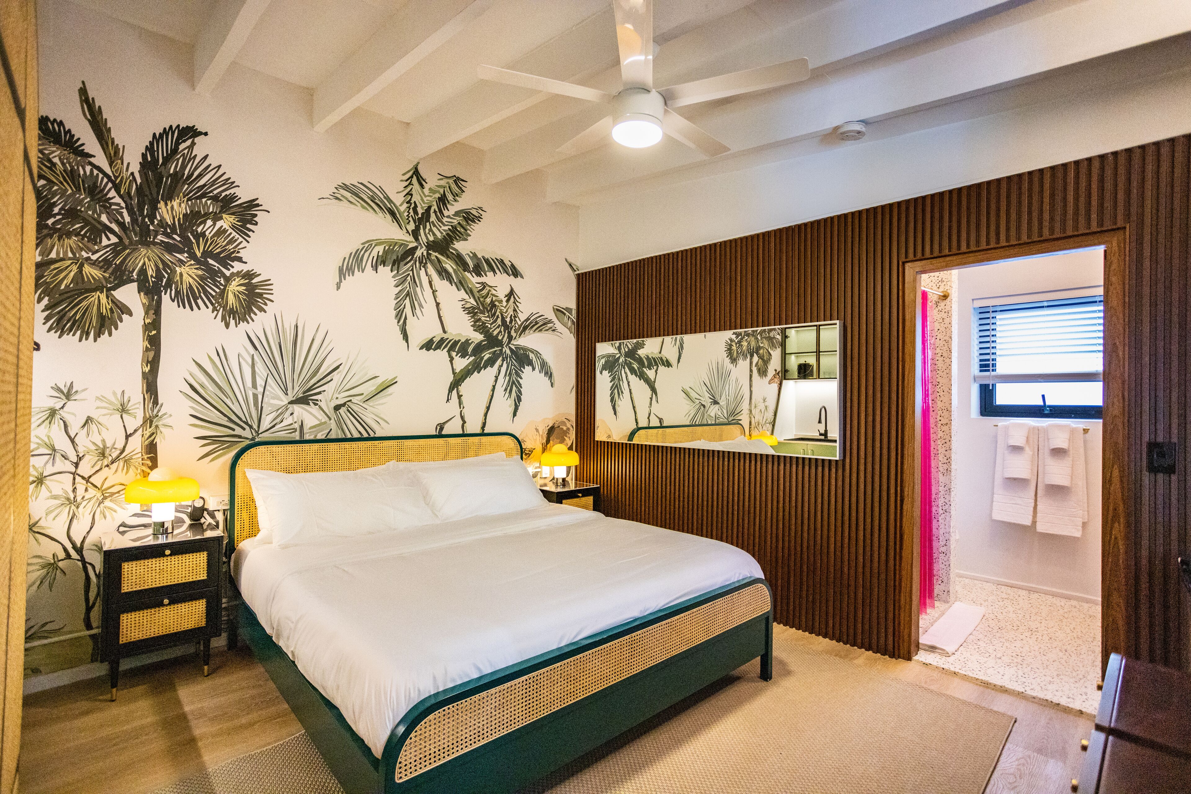 A bedroom with a bed, nightstands, a mirror, and a door leading to a bathroom.
