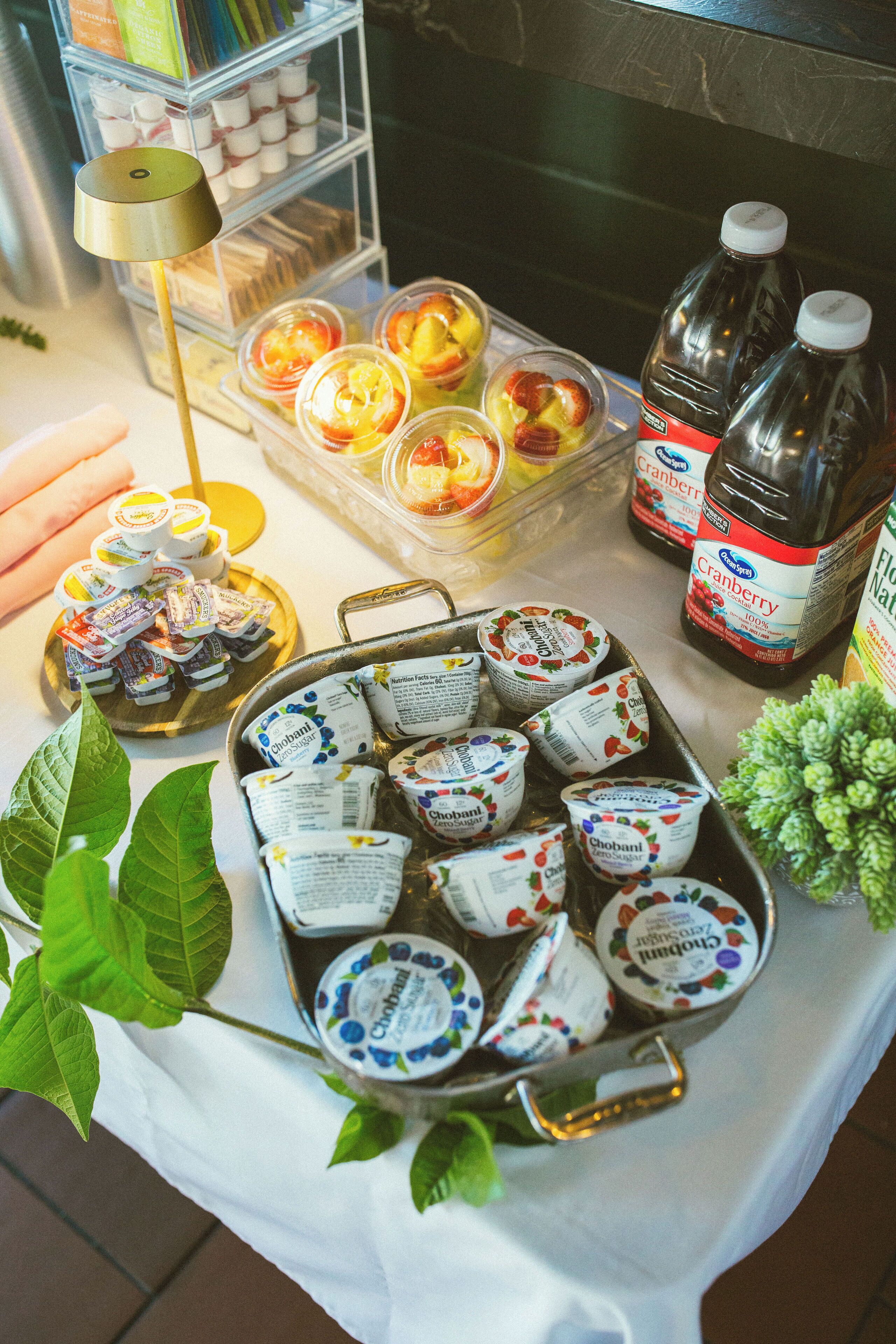 A table with various food items and drinks, including yogurt, juice, and bottles of cranberry juice.