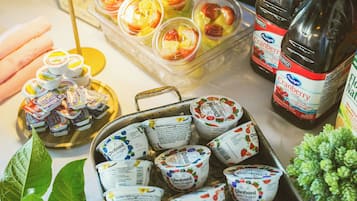 Une table sur laquelle sont disposés divers aliments et boissons, notamment du yaourt, du jus de fruits et des bouteilles de jus de canneberge.
