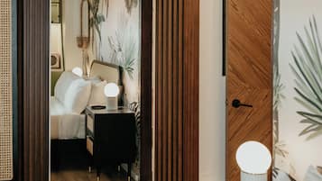 A bedroom with a wooden wardrobe, a bedside table with a lamp, and a bed with white bedding.