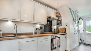 A modern kitchen with white cabinets, a wooden countertop, stainless steel appliances, and a built-in oven. - 2 bedroom accommodation in Freshwater East, near Pembroke (Freshwater East, near Pembroke)