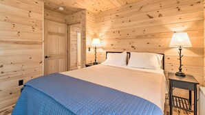Habitación con paneles de madera, una cama, dos lámparas de noche y una puerta.