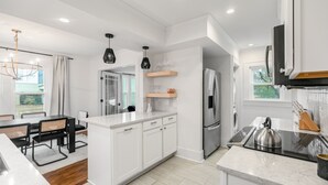 A modern kitchen with white cabinetry, a stainless steel refrigerator, a built-in oven, and a black countertop. - Location!! - The Davidson - Charming Home in Fayetteville Historic District (Fayetteville)