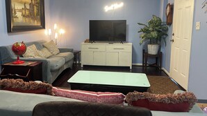 Una sala de estar con un sofá, una televisión, un aparador, un globo terráqueo y una planta.
