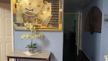 A hallway with a decorative wall piece, a small table with a vase of flowers, and a door leading to another room.