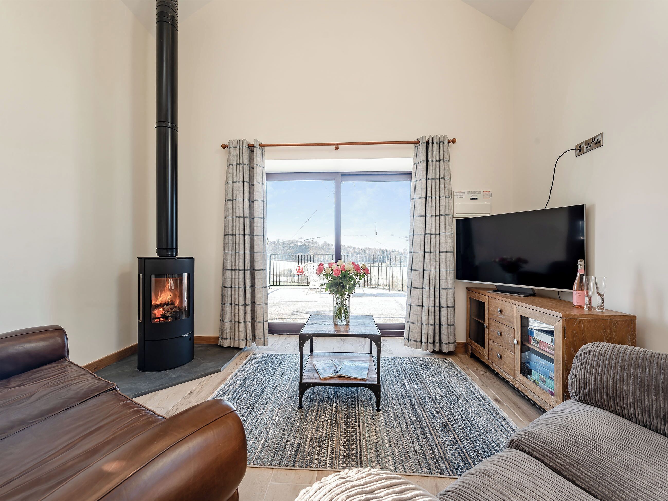 A living room with a fireplace, sofa, television, and a view through a glass door.