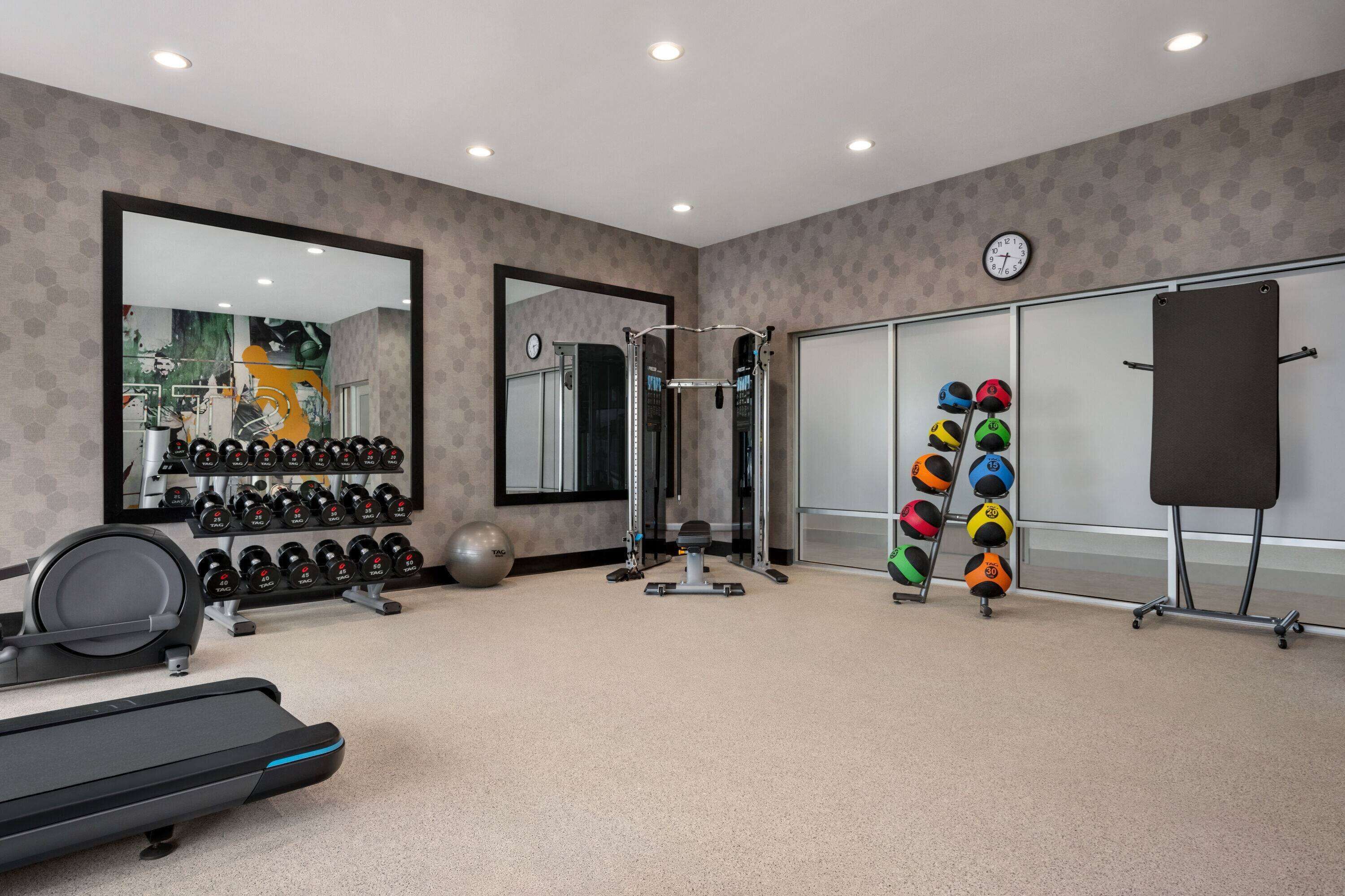 A gym with exercise equipment, a treadmill, and a mirrored wall.