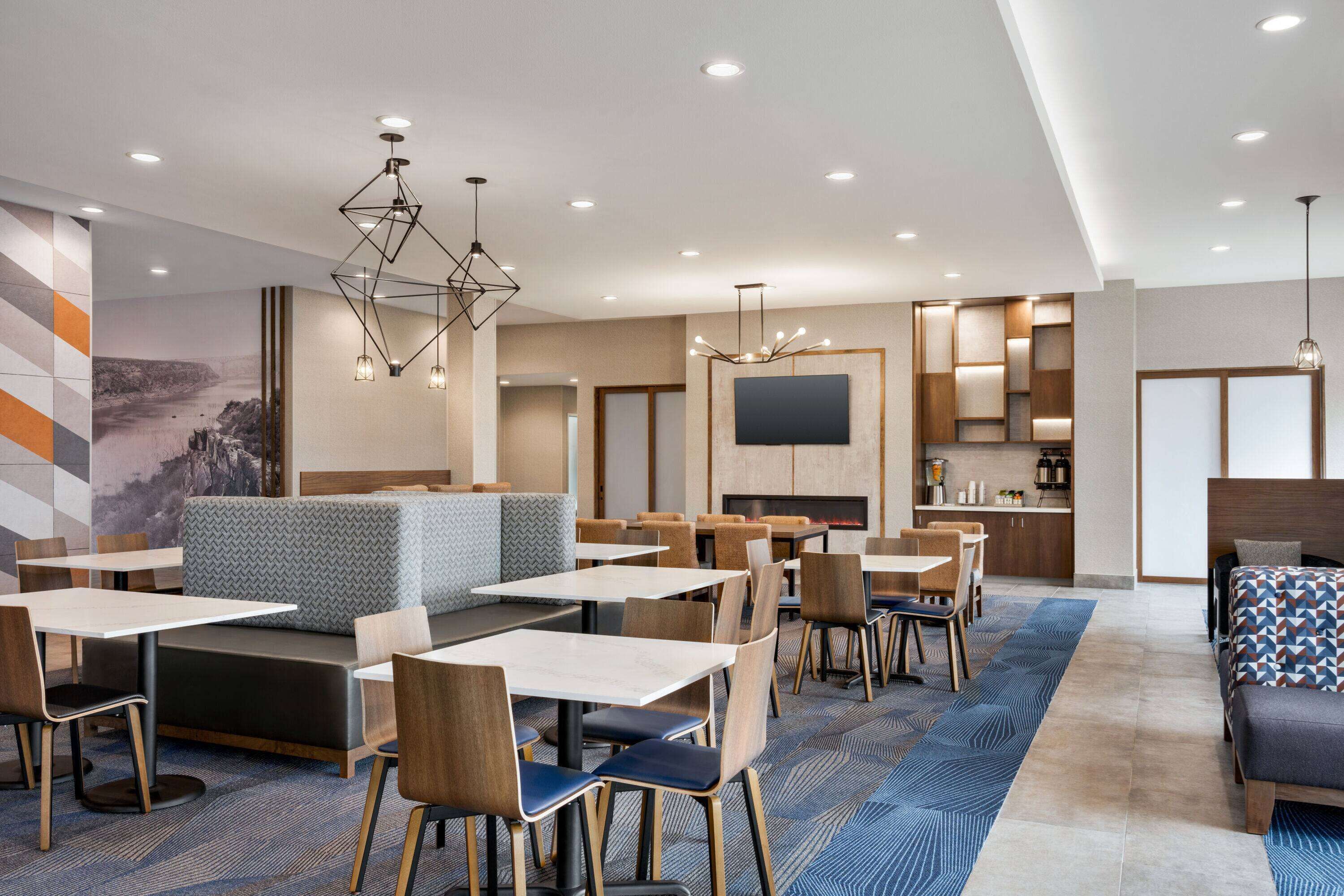 A modern hotel lobby with seating areas, tables, and a fireplace.