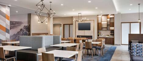 A modern hotel lobby with seating areas, tables, and a fireplace.