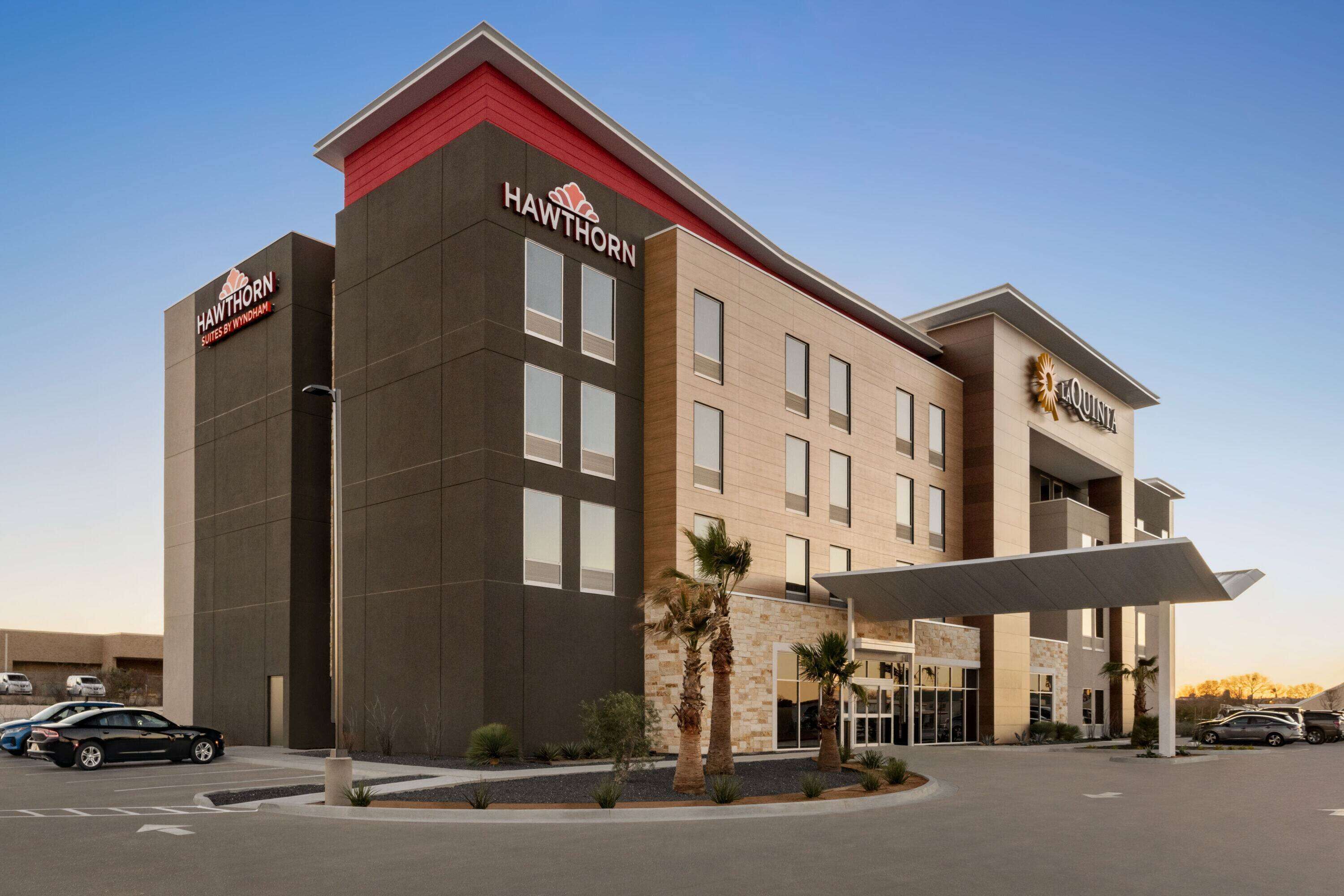 A modern hotel with a flat roof, a prominent sign, and a covered entrance.