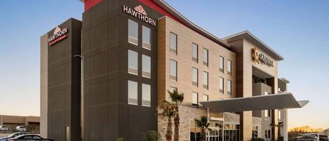 A modern hotel with a flat roof, a prominent sign, and a covered entrance.