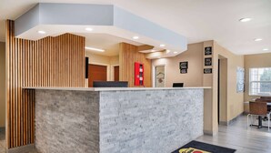 A reception area with a modern design, featuring a reception desk, a wooden slat wall, and a tiled floor. - Super 8 by Wyndham Joliet (Joliet)