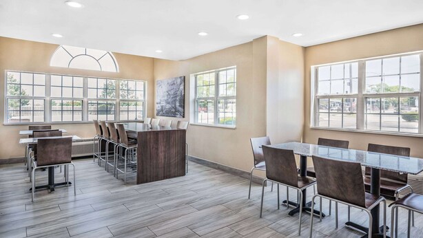 A spacious dining area with high ceilings, large windows, and modern furniture. - Super 8 by Wyndham Joliet (Joliet)