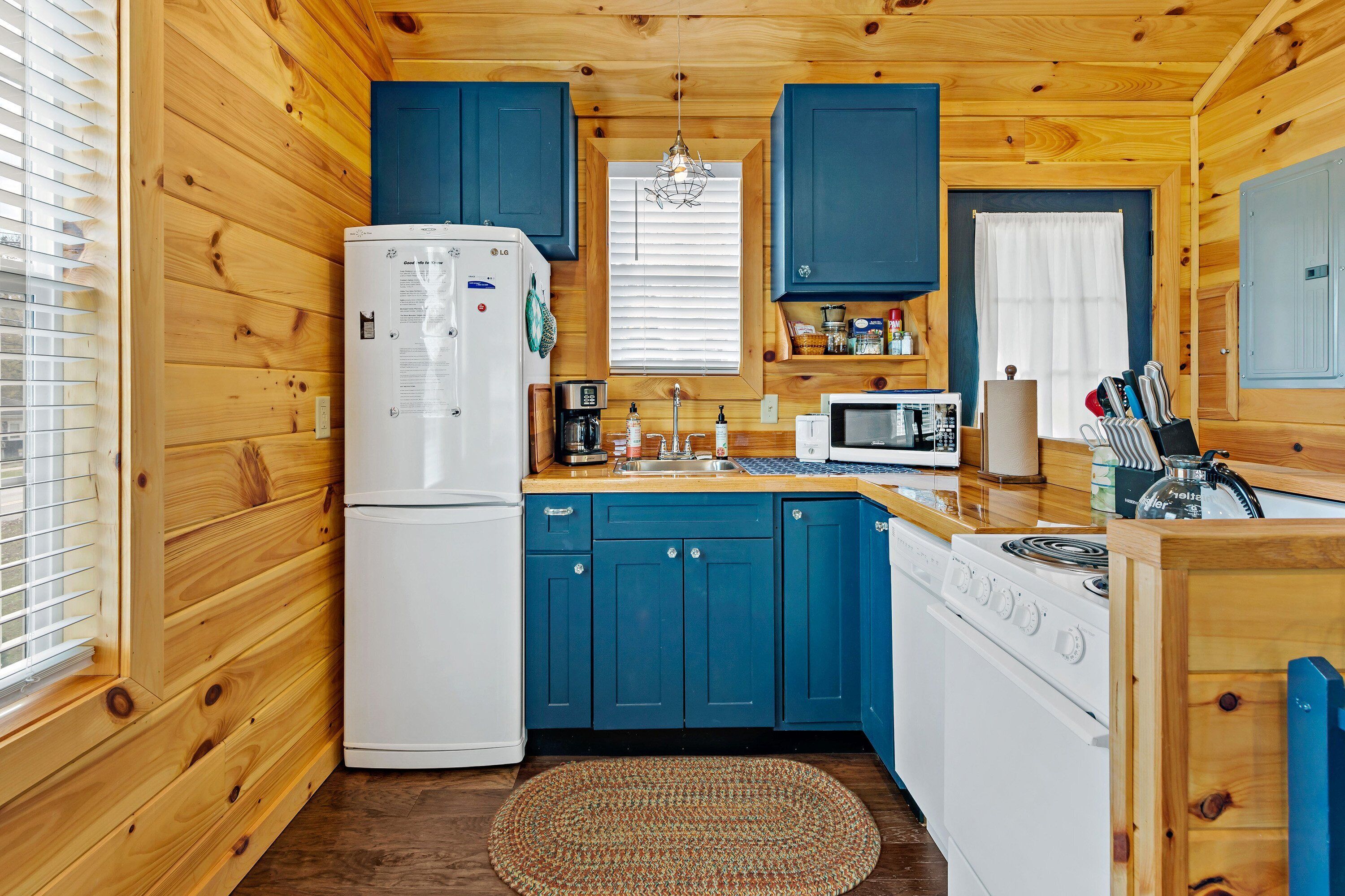 Una cocina compacta con paredes de madera, un refrigerador blanco, un microondas y una estufa.