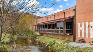 Un restaurante a orillas del río con terraza, edificio de ladrillo y vistas al río.