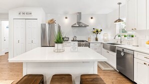 Una cocina moderna con una isla grande, electrodomésticos de acero inoxidable y muebles blancos.