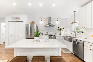 A modern kitchen with a large island, stainless steel appliances, and white cabinetry. - The Water's Edge, St. Augustine (Vilano Beach)
