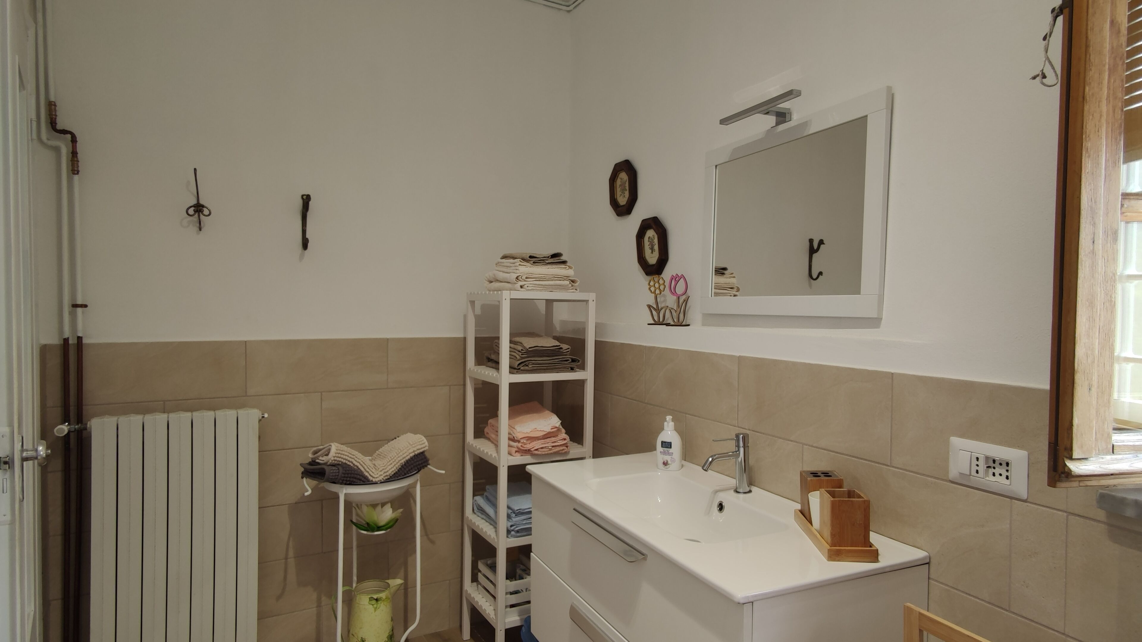 Ein Badezimmer mit einem weißen Waschbecken, einem Spiegel, einem Handtuchhalter und einer Heizung.