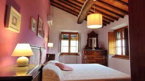 Une chambre à coucher avec un lit, une commode, un miroir et une fenêtre avec des volets.