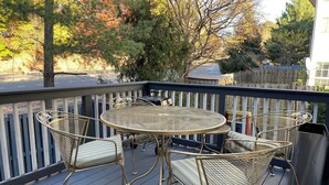 A deck with a round table and four chairs, surrounded by a wooden fence. - Comfy Luxury Vacation Getaway (Dumfries)