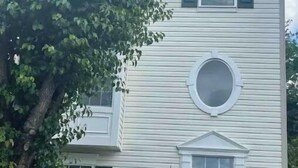 A two-story house with a circular window on the second floor, a front door with a small porch, and a mailbox with the number 3201. - Comfy Luxury Vacation Getaway (Dumfries)