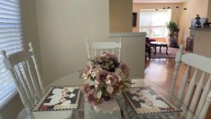 A dining area with a glass table surrounded by white chairs, a floral centerpiece, and a patterned table runner. - Comfy Luxury Vacation Getaway (Dumfries)
