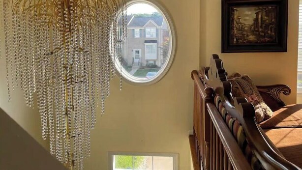 A room with a large, ornate chandelier, a round window with a view of a house, and a framed painting on the wall. - Comfy Luxury Vacation Getaway (Dumfries)