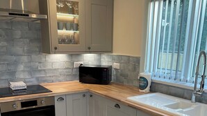 A modern kitchen with grey cabinets, a black microwave, and a stainless steel oven. - 3 bedroom accommodation in Fraisthorpe, near Bridlington (Fraisthorpe, near Bridlington)